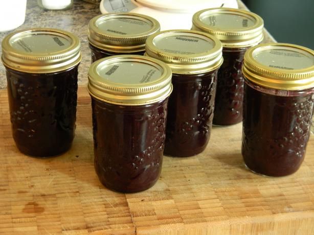 six jars of jam sit on a cutting board