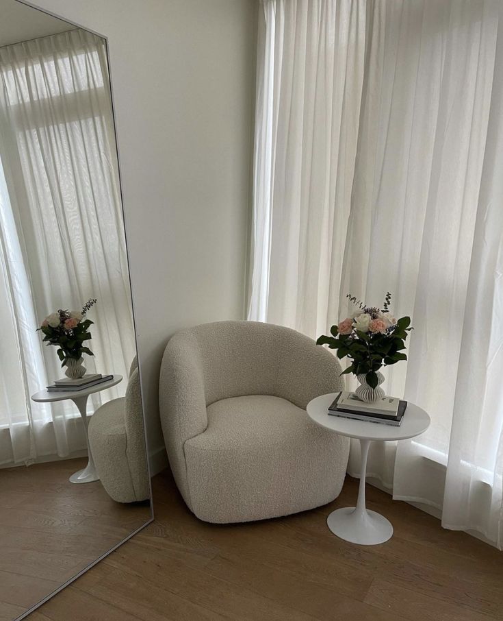 a white chair sitting in front of a mirror on top of a hard wood floor