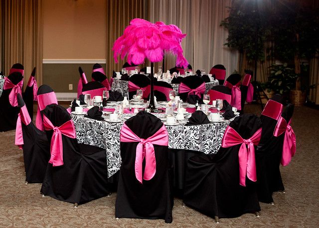 a banquet room with black and pink chairs, table cloths, and centerpieces