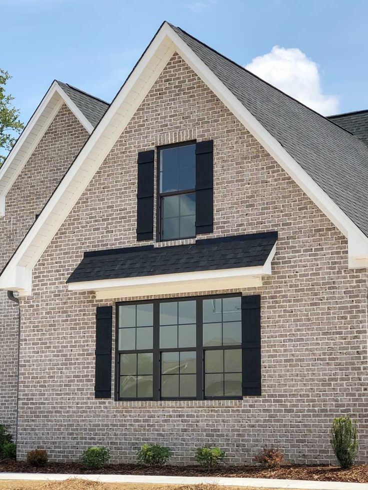 a brick house with black shutters and white trim