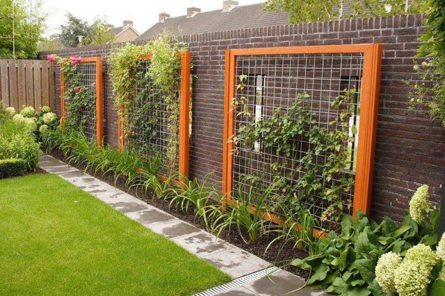 a fenced in garden with lots of plants and flowers on the side of it