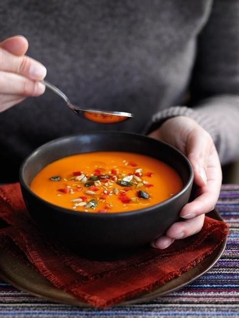 a person is holding a spoon over a bowl of soup