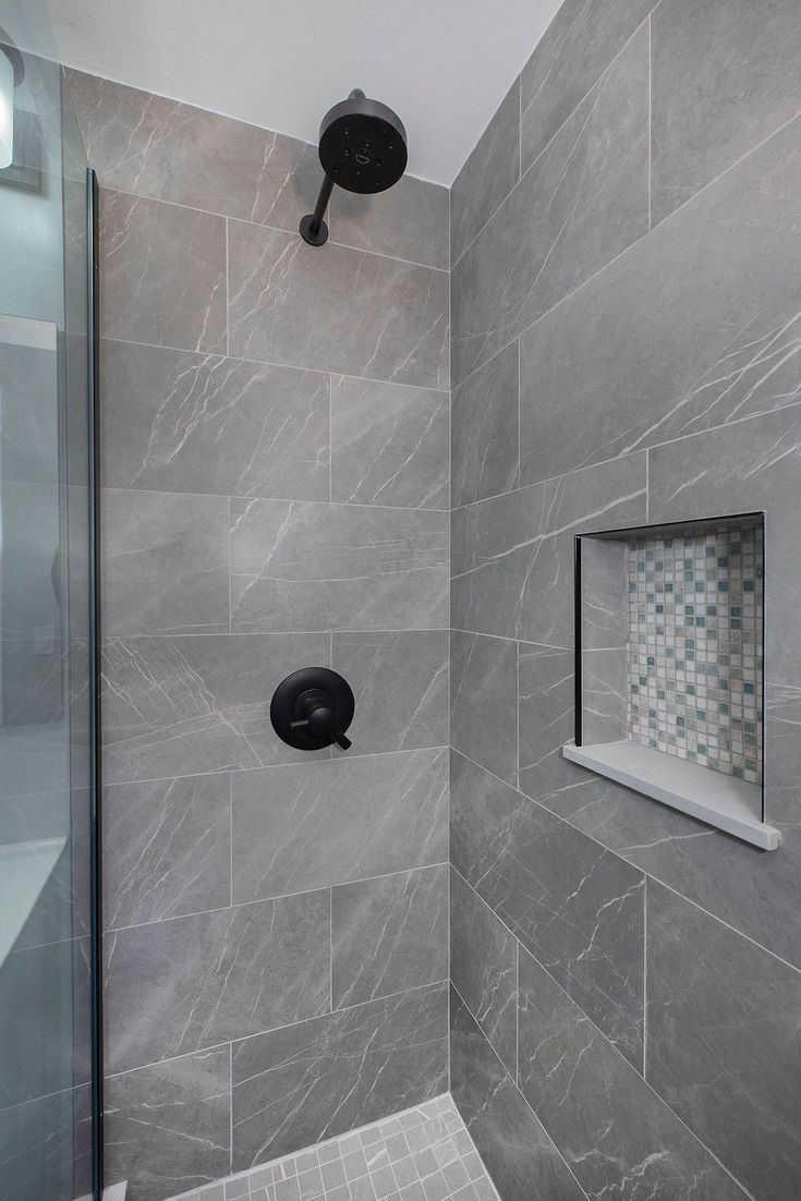 a walk in shower sitting next to a tiled wall