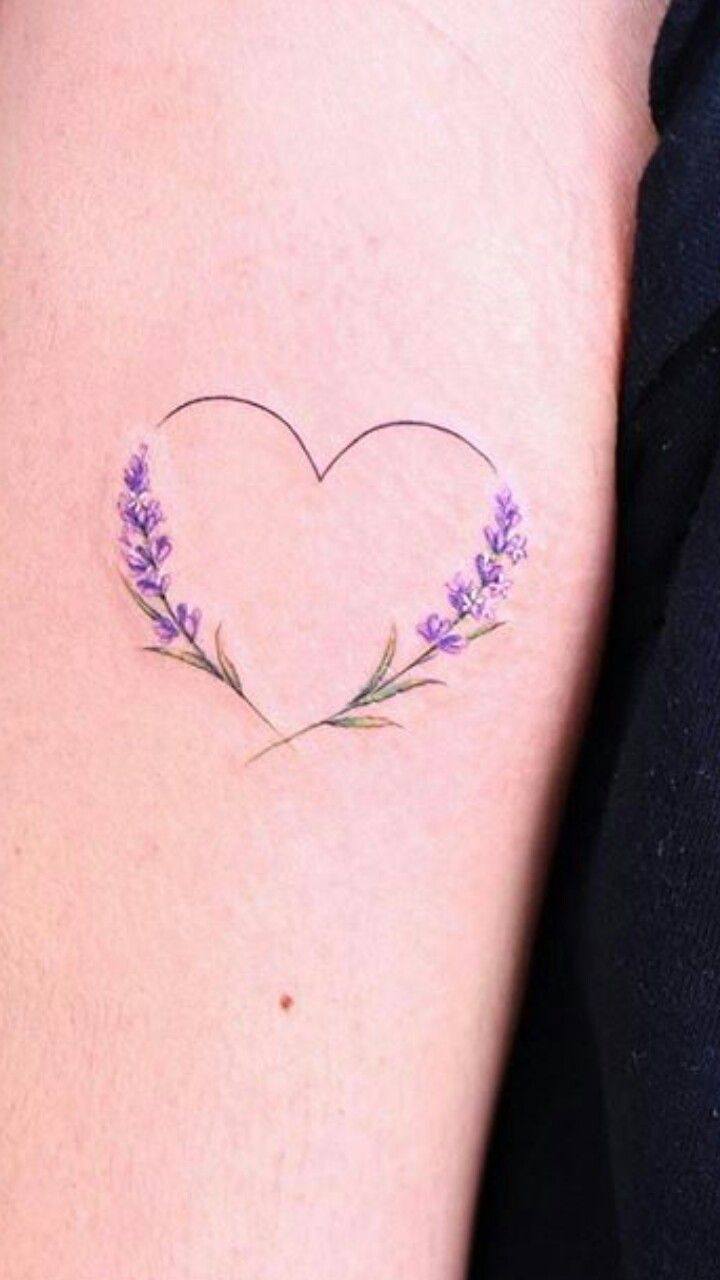 a heart shaped tattoo with lavender flowers on the left side of the arm and behind it