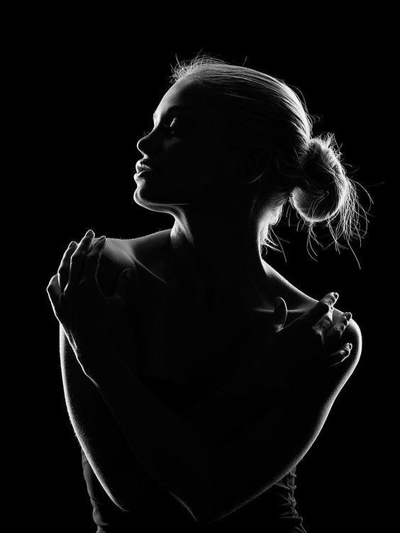 a black and white photo of a woman with her arms folded in the shape of a heart