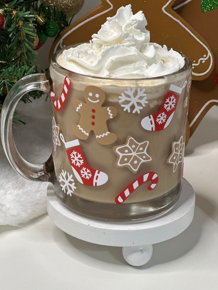 a glass mug filled with whipped cream and decorated gingerbreads