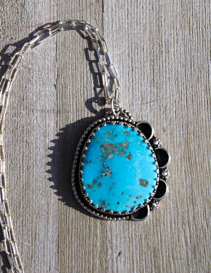 "Extra large Kingman Turquoise cab from Arizona. Vibrant blue with Pyrite inclusions. Set in a handmade Sterling Silver setting with Princess crown bezel and dotted wire border with tiny Sterling daisies and petals. Chunky Sterling Silver paper clip chain is 18\" long. I previously had this labeled as Campitos Turquoise. I had it in the wrong drawer. I am SO glad I double checked! This is a Kingman cab. ❤️❤️❤️" Handmade Blue Turquoise Necklace With Round Pendant, Unique Handmade Blue Turquoise Necklace, Blue Turquoise Necklace For Jewelry Making, Artisan Blue Turquoise Necklace Nickel Free, Bohemian Turquoise Necklace With Large Blue Stone, Nickel Free Blue Turquoise Necklace With Round Pendant, One Of A Kind Oval Turquoise Necklace, Unique Blue Turquoise Necklace, Vintage Blue Turquoise Necklace Nickel Free