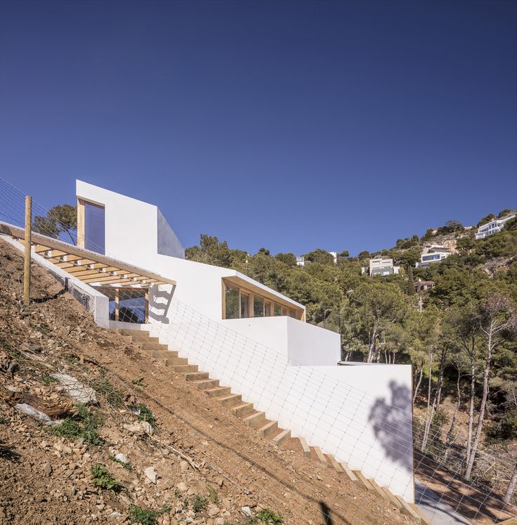 the stairs lead up to the upper level of this modern home on a steep slope