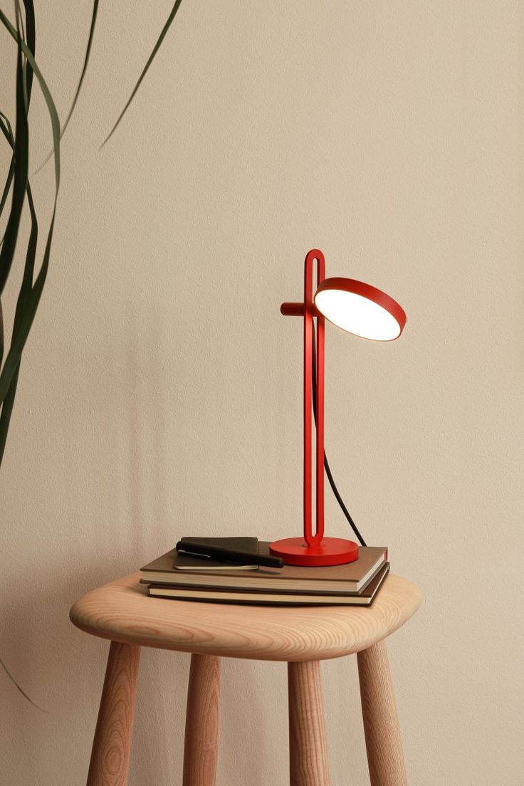 a red lamp sitting on top of a wooden table next to a potted plant