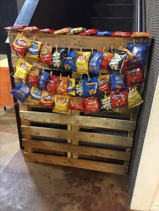 a wooden pallet filled with chips and candy bar wrappers hanging from it's sides