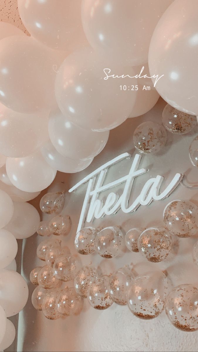 there is a sign that says thea surrounded by white balloons and other things in front of it