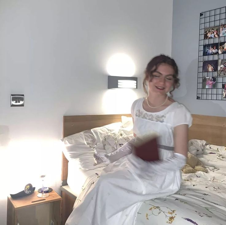 a woman in white dress sitting on a bed