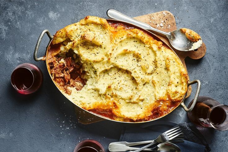 a casserole dish with meat, cheese and sauce in it on a table