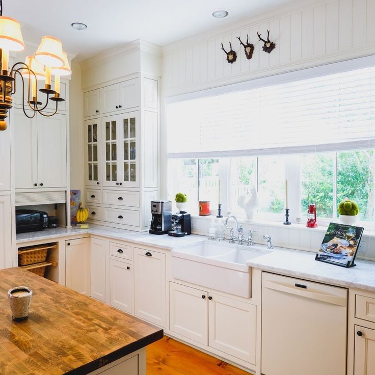 a kitchen with white cabinets and wooden counter tops