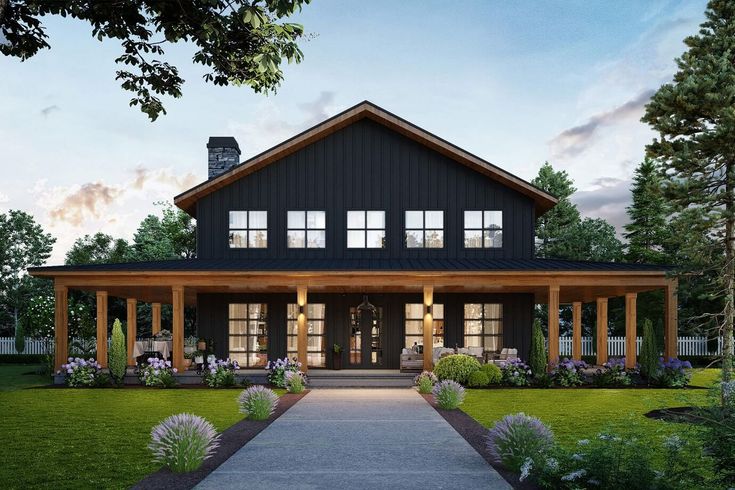 a black and white house with lots of windows on the front porch is lit up at night