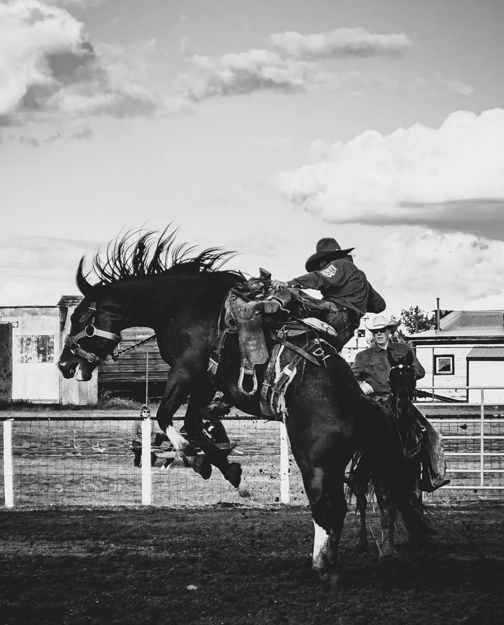 a man riding on the back of a brown horse in a fenced in area