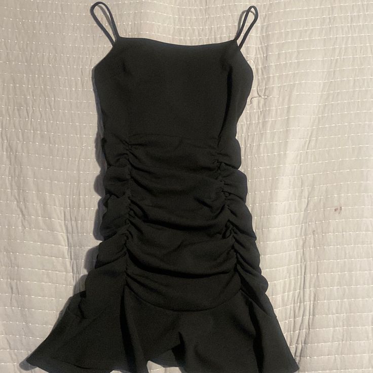 a black dress laying on top of a bed