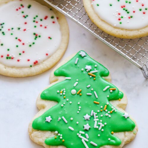 cookies decorated with green icing and sprinkles are on a cooling rack