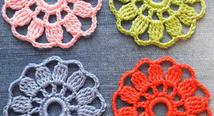 four crocheted flowers are shown in different colors and sizes on a blue surface