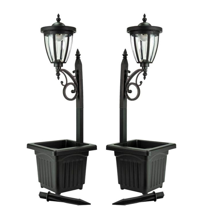 two black planters sitting next to each other on top of a light pole and lamp post