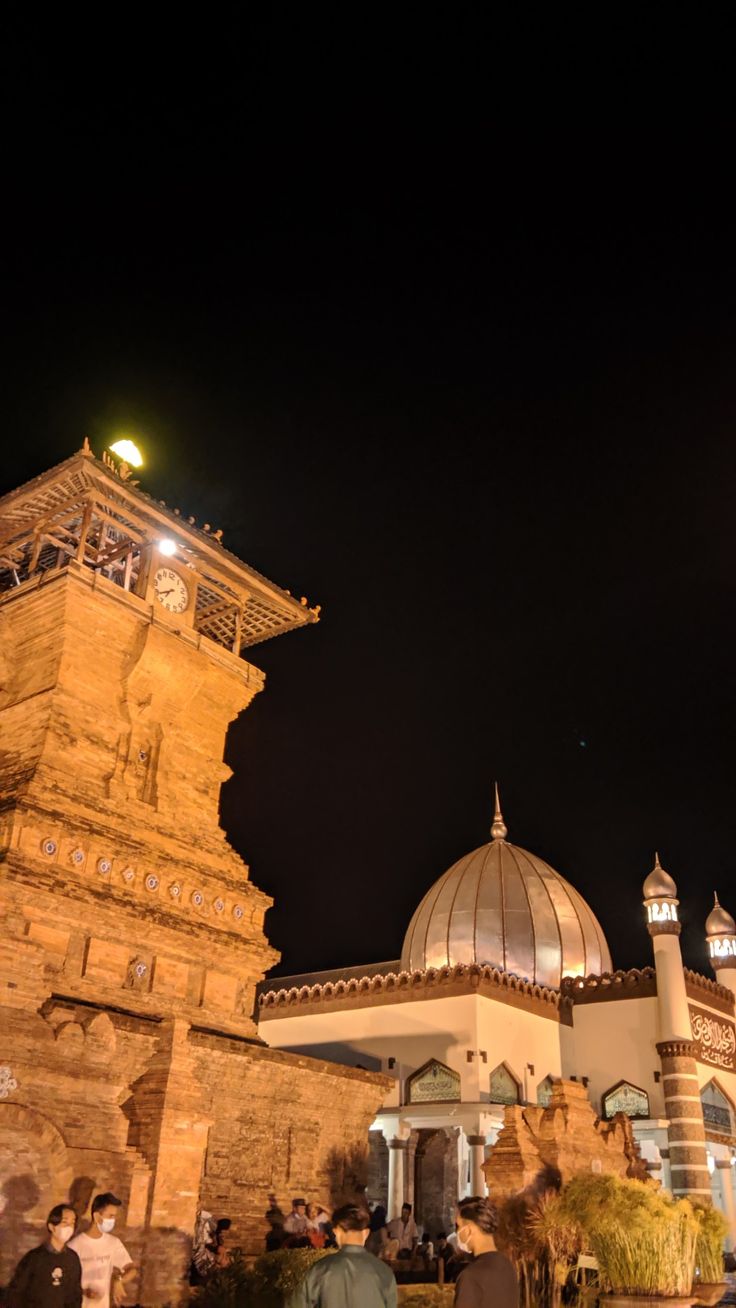 people are standing in front of an old building at night with lights on the dome