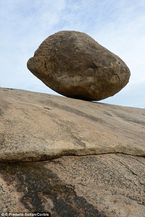 a rock sitting on top of a large boulder