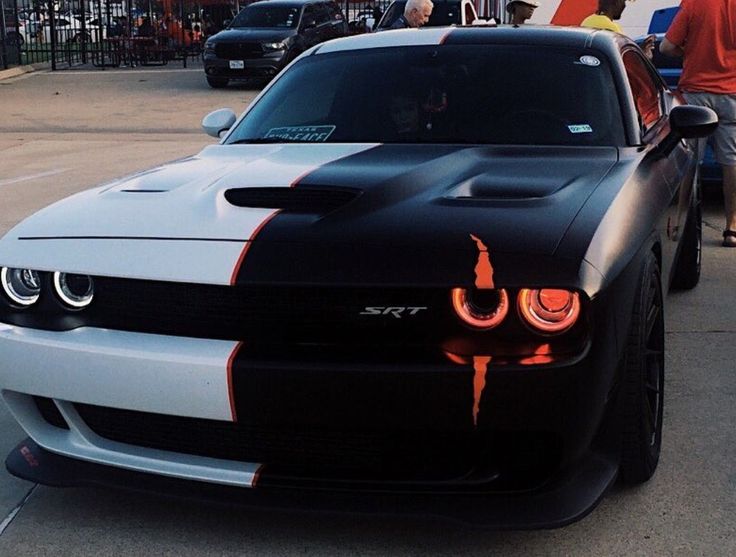 a black and white sports car with orange flames on it's hood is parked in a parking lot