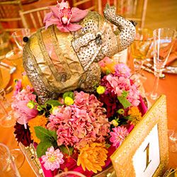 an elephant statue sitting on top of a wooden box filled with flowers and candles at a table