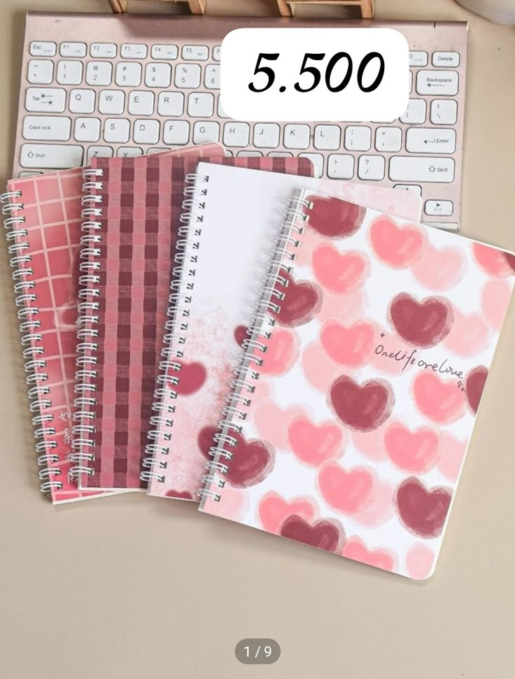 three notebooks sitting next to each other on top of a desk with a keyboard