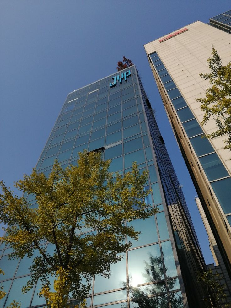 two tall buildings with trees in front of them