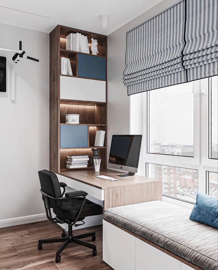 a desk with a computer on top of it next to a window in a room