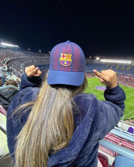 a person with long hair wearing a hat at a soccer game in the stadium,