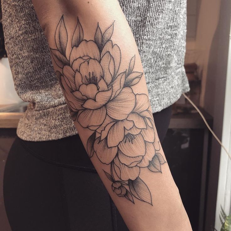 a woman's arm with a flower tattoo on the left side of her arm