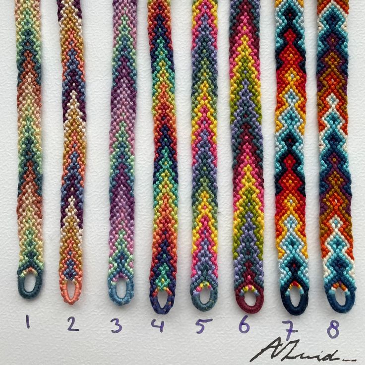 five different colored bracelets are lined up on a white surface with numbers in the middle