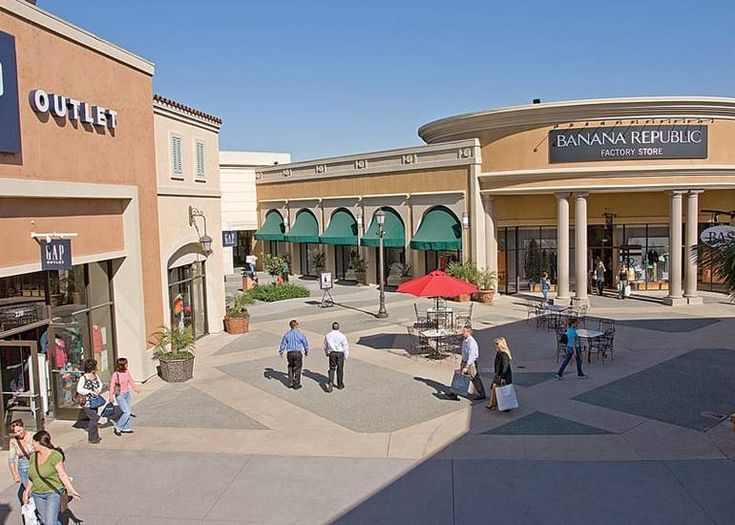 people are walking around in front of shops on a sunny day with blue skies overhead