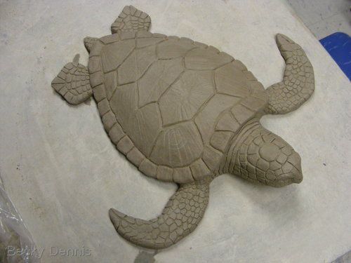 a sand sculpture of a turtle sitting on the ground with it's eyes closed