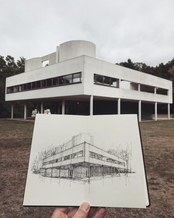 someone holding up a drawing in front of a building