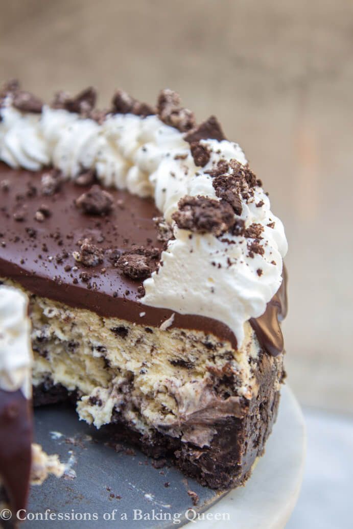 a chocolate cake with white frosting and oreo cookies on top is cut in half