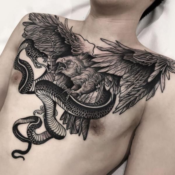 a man's chest with an eagle and snake tattoo on his chest, in black ink