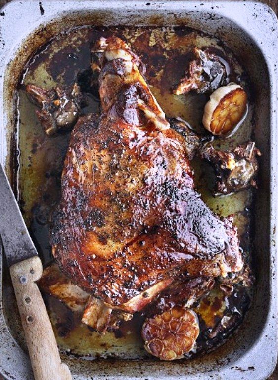 a roasting pan filled with cooked meat and vegetables on top of a wooden table