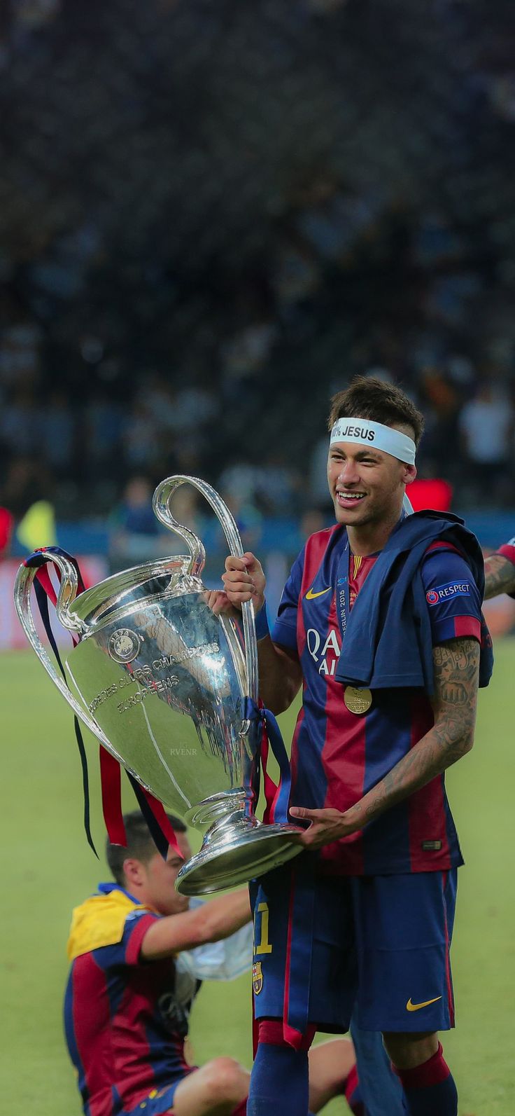 a soccer player holding the trophy in front of his face and two other players behind him