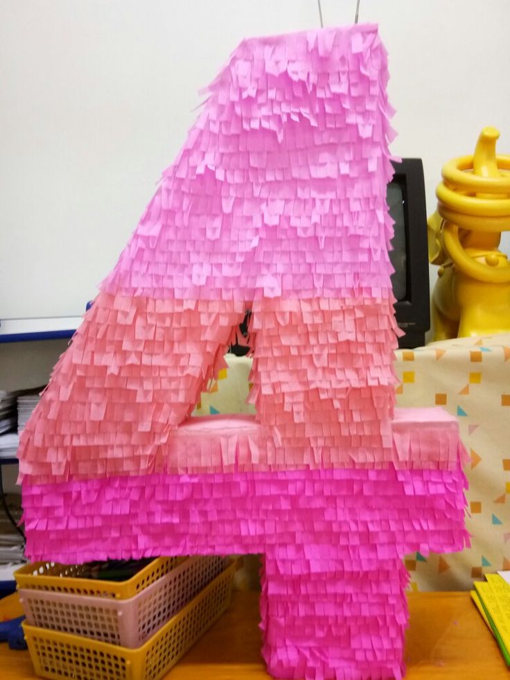 the number four is made out of pink and yellow strips of tissue paper on top of a wooden table