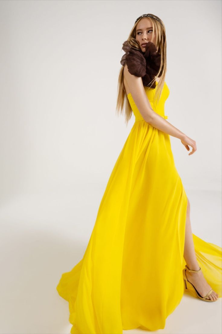 a woman in a long yellow dress posing for the camera with her hand on her hip