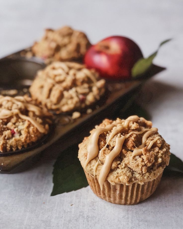 some muffins are sitting on a tray next to an apple