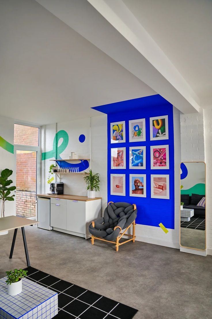 a living room filled with furniture and pictures on the wall next to a kitchen area