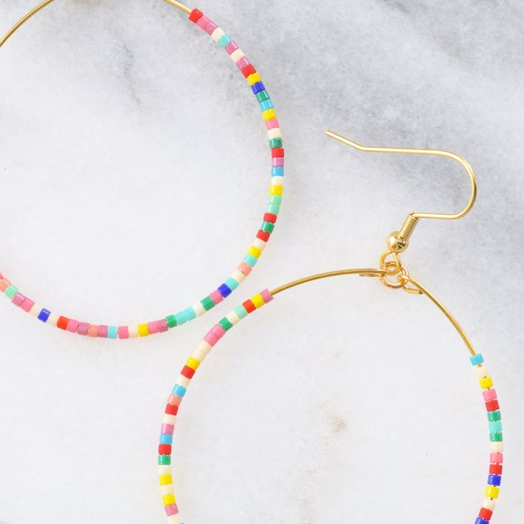 You asked for bigger beaded hoops and Libby & Smee answered! These dangly seed bead hoop earrings are the pieces you'll grab every day when you want a little something fun without a lot of fuss. Bonus: They look great dressed up or super casual. It's no surprise that they've become the Libby & Smee cult favorite. beaded hoops with tiny glass seed beads available in two large sizes: BIG, a teardrop shape approximately 1.75 inches wide and 2.75 inches long, or BIGGER, a circle shape 2.25 inches wi Star Charm Necklace, Plastic Earrings, Rainbow Beads, Rainbow Earrings, Earring Cards, Beading Wire, Metallic Pink, Beaded Hoop Earrings, Bohemian Earrings