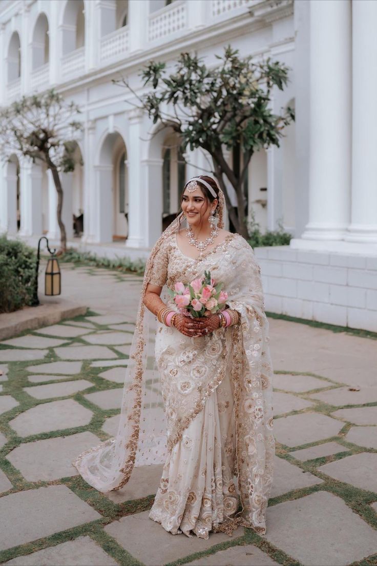 a woman standing in front of a white building wearing a bridal gown and veil