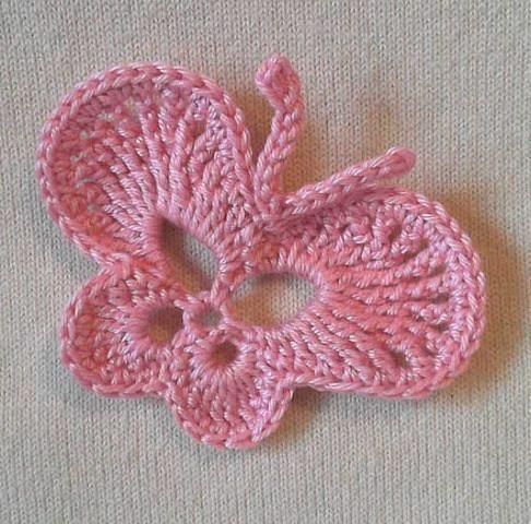 a pink crocheted flower on top of a table