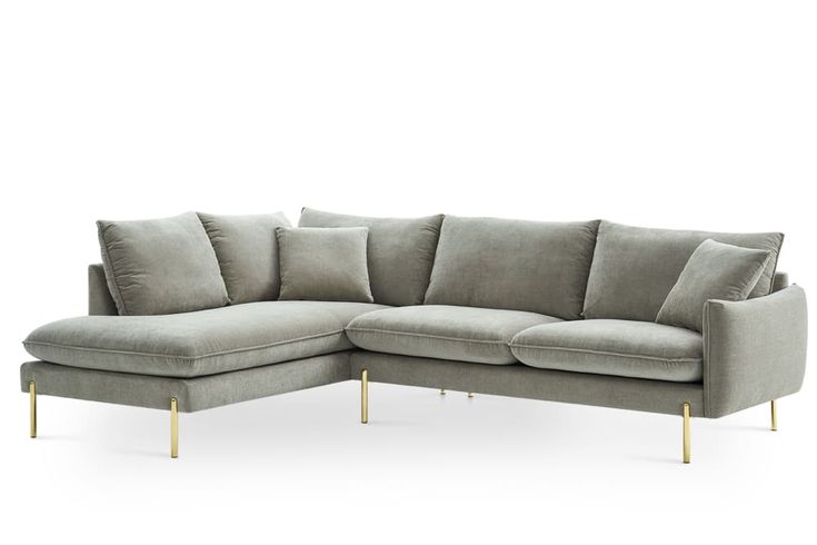 a gray sectional sofa with gold legs and pillows on the back, in front of a white background