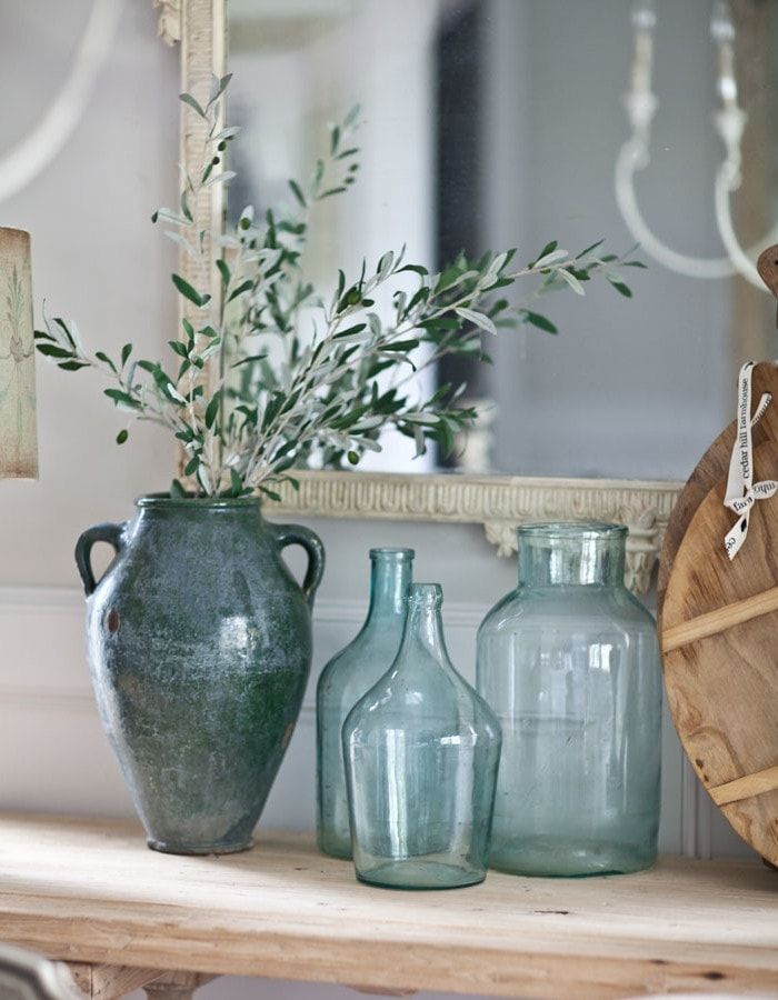 three vases sitting on top of a wooden table next to a mirror and plant